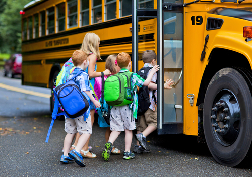 group of five students getting on school bus