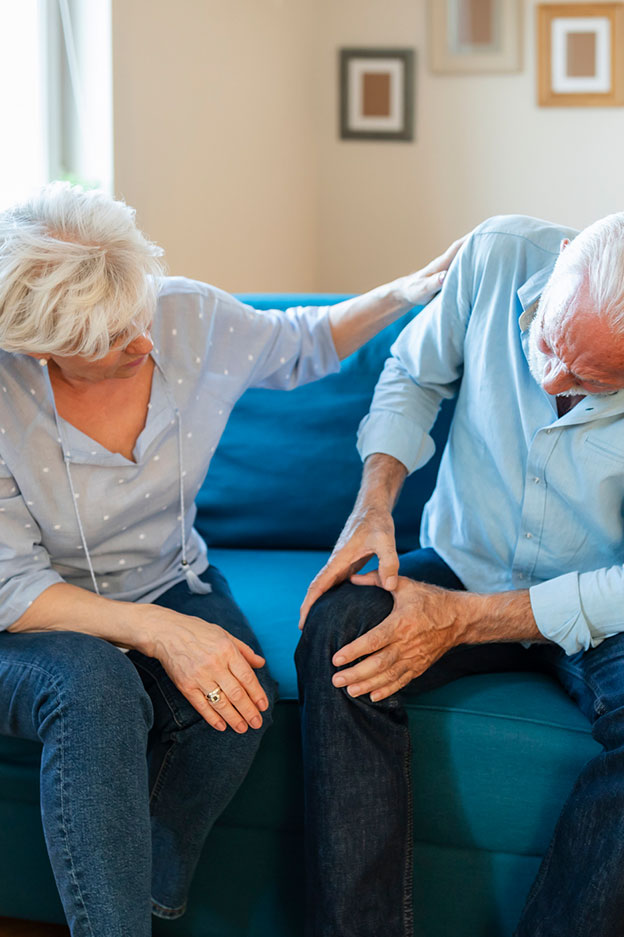 Mujer anciana consolando al viejo con dolor de rodilla