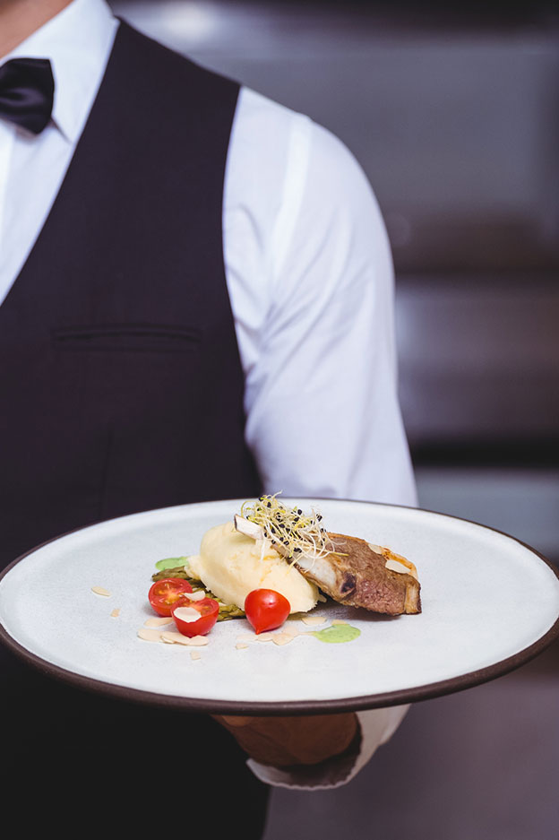 close up of waiter serving food in restaurant